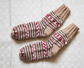 Pair of warm woolen colorful knitted socks on a linen background