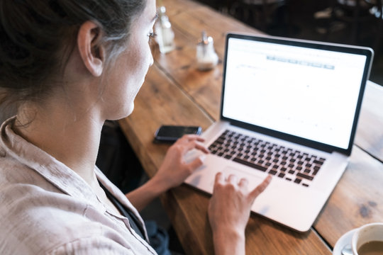 Woman working on laptop while sitting in coffee shop