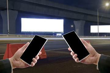 Smartphone / View of hand of businessmen holding smartphone with billboard at night for advertisement background.