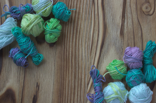 Many small multicolor melange cotton yarn balls for knitting, crochet. Wooden rustic background
