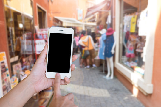 Hands woman are holding touch screen smart phone,tablet on blurred people shopping on street markets old building style background.