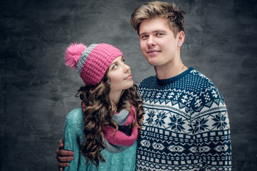 Urban couple in sweaters on grey background.