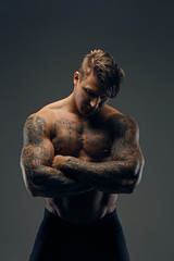 Tattooed muscular male with crossed arms.