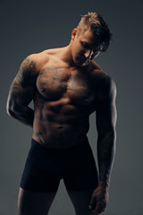 Fototapeta na wymiar Portrait of tattooed muscular male in a shadow.