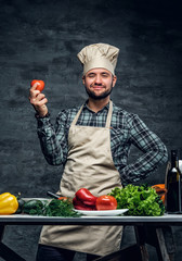 A cook man with fresh vegetables on a table.