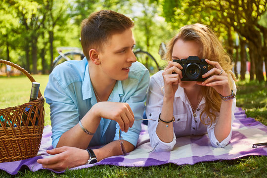 Couple using a compact photo camera at a picnic.