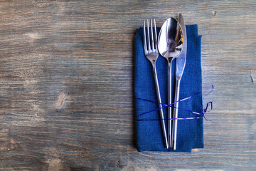 Concept of simple organic food - laconic design cutlery set on rustic wooden table and linen tissue. Top view.