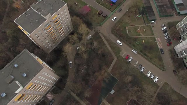 Top aerial view of one of Moscow yard with road traffic and sports playground, cloudy spring weather. Urban cityscape from quadrocopter