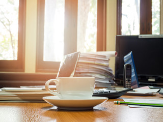 A cup of coffee and office supplies in meeting room at morning