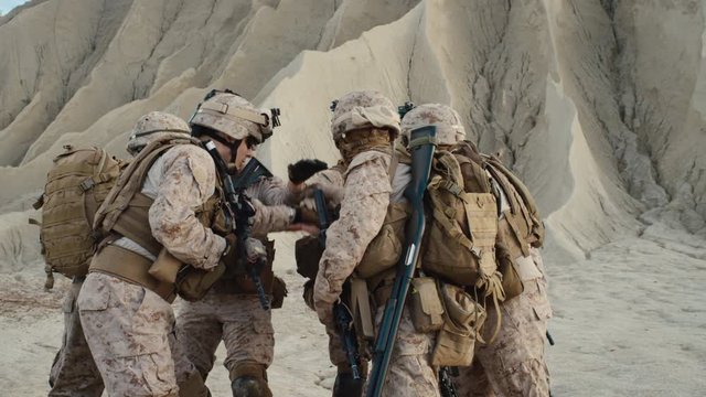 Group of Soldiers are Standing in a Circle and Staking Hands as Symbol of Team at the end of Briefing before Military Operation in the Desert. Slow Motion.