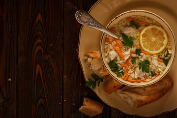 Chicken soup with pasta on a dark wooden background.