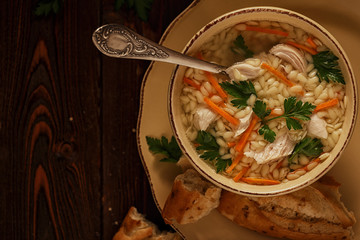 Chicken soup with pasta on a dark wooden background.
