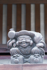 Takayama, Japan - September 24, 2016: Brown statue partly covered in white dust of the laughing iconic Japanese God of Good Luck, Ebisu. Brown and white background.