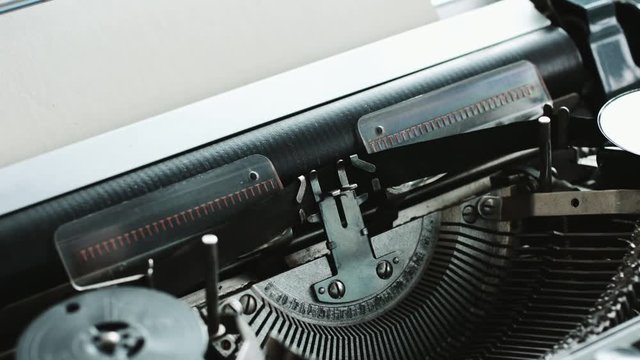 Close-up of man hands loads blank sheet of paper in vintage typewriter