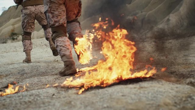 Close-up Shot of Soldiers Running on Burning Ground in the Desert. Slow Motion.