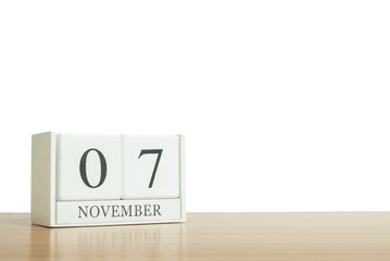 Closeup surface white wooden calendar with black 7 november word on blurred brown wood desk isolated on white background with copy space , selective focus at the calendar