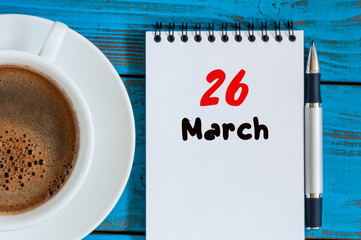 March 26th. Day 26 of month, calendar on blue wooden table background with morning coffee cup....