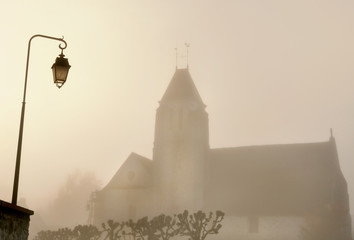 lampadaire devant une église d'un village dans la brume 