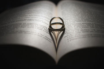 Fototapeta premium Wedding rings and heart shadow on an open book