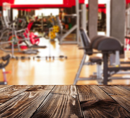 Wooden table against blurred gym interior background. Sport and healthcare concept.