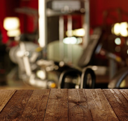 Wooden table against blurred gym interior background. Sport and healthcare concept.