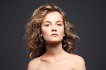 Obraz premium Portrait of beautiful young woman with long hair on grey background
