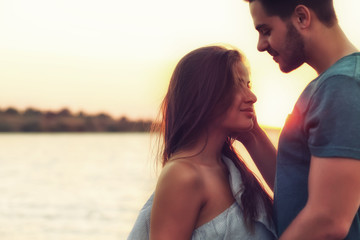 Young couple in love sensually embracing on the beach at sunset