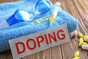 Sports equipment, word Doping and syringe on wooden background