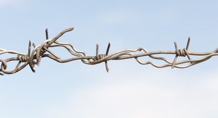 Barbed wire on a wooden post against blue sky