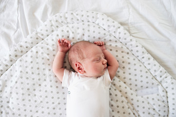 Newborn baby boy lying on bed, sleeping, close up