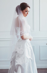 Beautiful bride with fashion wedding hairstyle - on white background. Portrait of young woman. Studio shot. Girl veil over her face