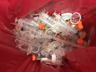 In an HIV testing laboratory, single-use plastic syringes, pipettes, and filters are disposed of in a red hazardous materials waste bag.
