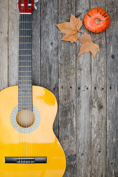 winter music symbol with autumn leaves and guitar on old wooden plank