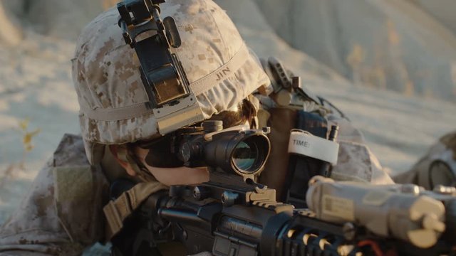 Close-up of Soldier Lies Down on the Hill, Aims through the Assault Rifle Scope in Desert Environment. Slow Motion. Shot on RED EPIC Cinema Camera in 4K (UHD)