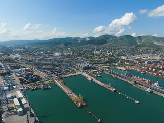 Fototapeta premium Industrial seaport, top view. Port cranes and cargo ships and barges. Loading and shipment of cargo at the port. View of the sea cargo port with a bird's eye view