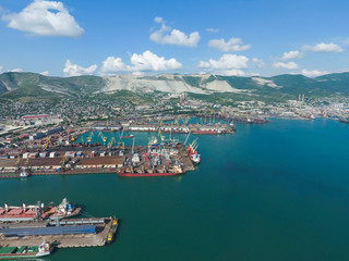 Fototapeta na wymiar Industrial seaport, top view. Port cranes and cargo ships and barges. Loading and shipment of cargo at the port. View of the sea cargo port with a bird's eye view
