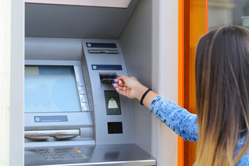 young woman inserting credit card at ATM