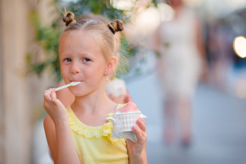 Little girl eating ice-cream outdoors at summer. Cute kid enjoying real italian gelato near...
