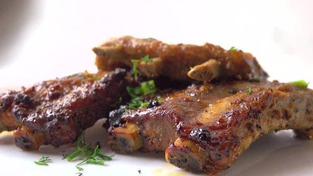 Pouring green herbs on freshly cooked meat. Cooking spare ribs. 4K close-up video