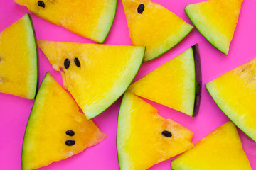 Naklejka na ściany i meble Slices of yellow watermelon on pink background. Top view.
