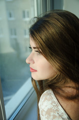 beautiful girl with long brown hair looking in the window