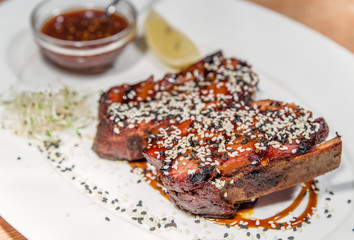 Grilled meat ribs on white plate with   sauce