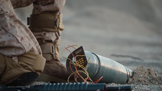 Close-up of Soldier Defusing a Bomb by Cutting a Wire During Military Operation in Desert Environment