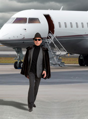Handsome business man near a private jet wearing a hat.