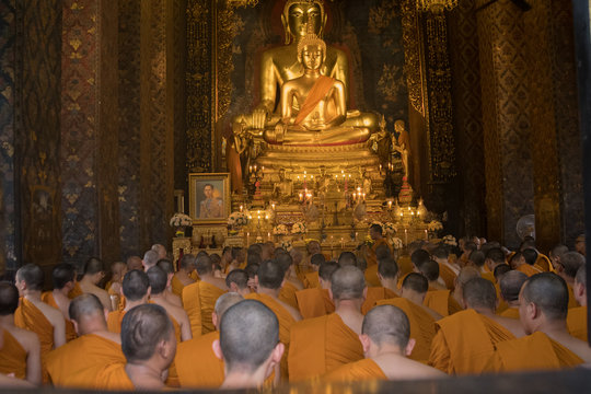Buddha statue and Buddhist monk chanting in Wat Bovoranives, Bangkok, Thailand. Photo taken on: October 30, 2016
