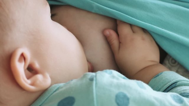 Mother feeds her baby breast milk and lulls baby