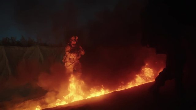 Group of Armed Soldiers Running through Fire During Night Military Operation. Slow Motion.