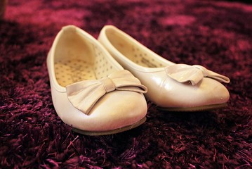Children's shoes - shoes of little bridesmaid lying on a scarlet velvet