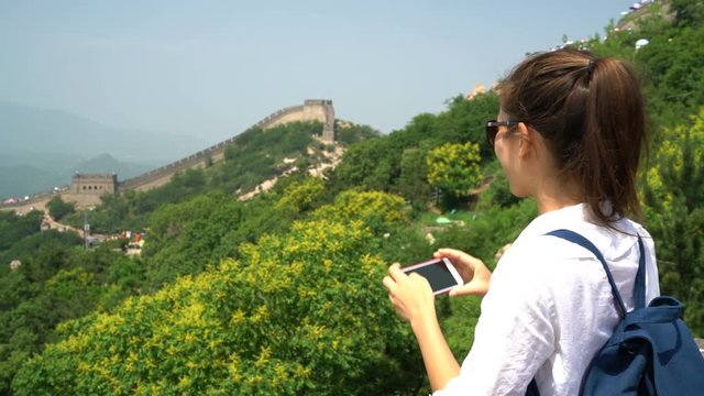 Great Wall of China. Tourist taking photo at famous Badaling during travel vacation holidays at Chinese tourist destination. Woman tourist taking picture using smart phone in Asia.