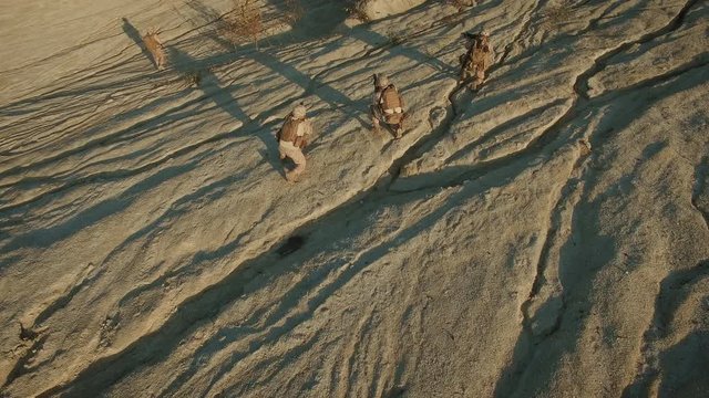 Flying over Group of Running Soldiers During Military Operation in Desert Environment.